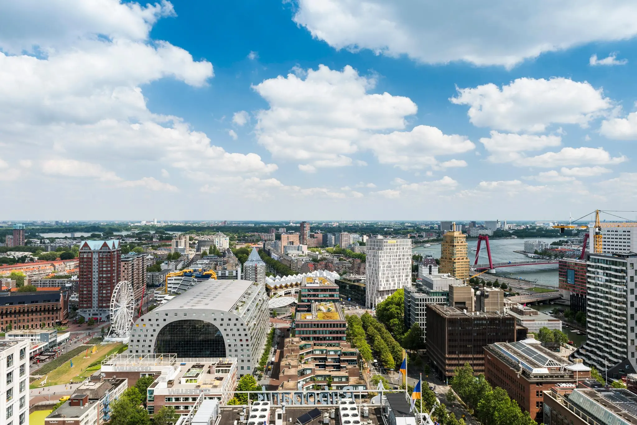 Luchtfoto van het centrum van Rotterdam met de Markthal, kubuswoningen en de Willemsbrug.