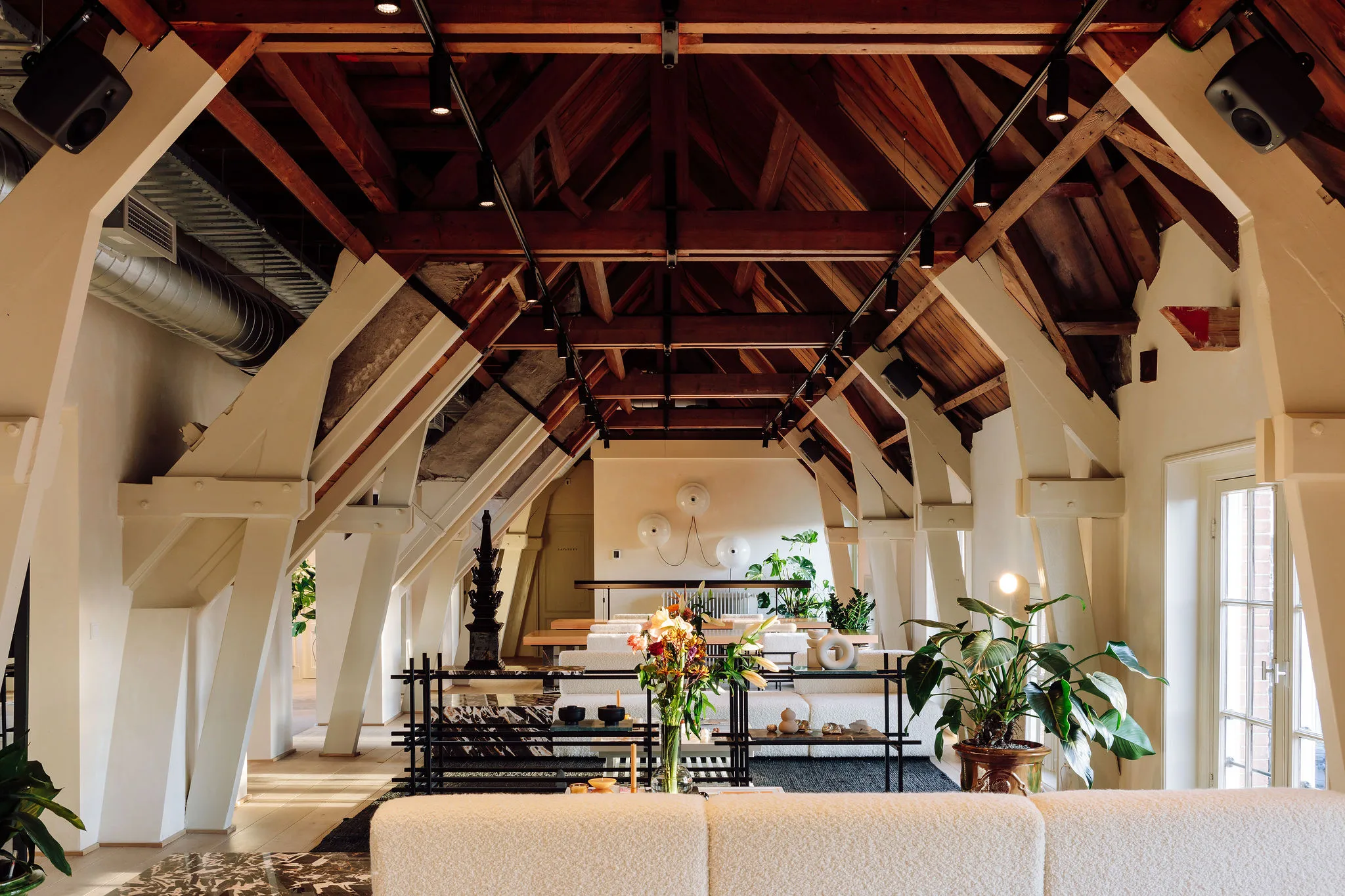 Een sfeervolle, moderne loft met houten balken, stijlvolle meubels, en groene planten.