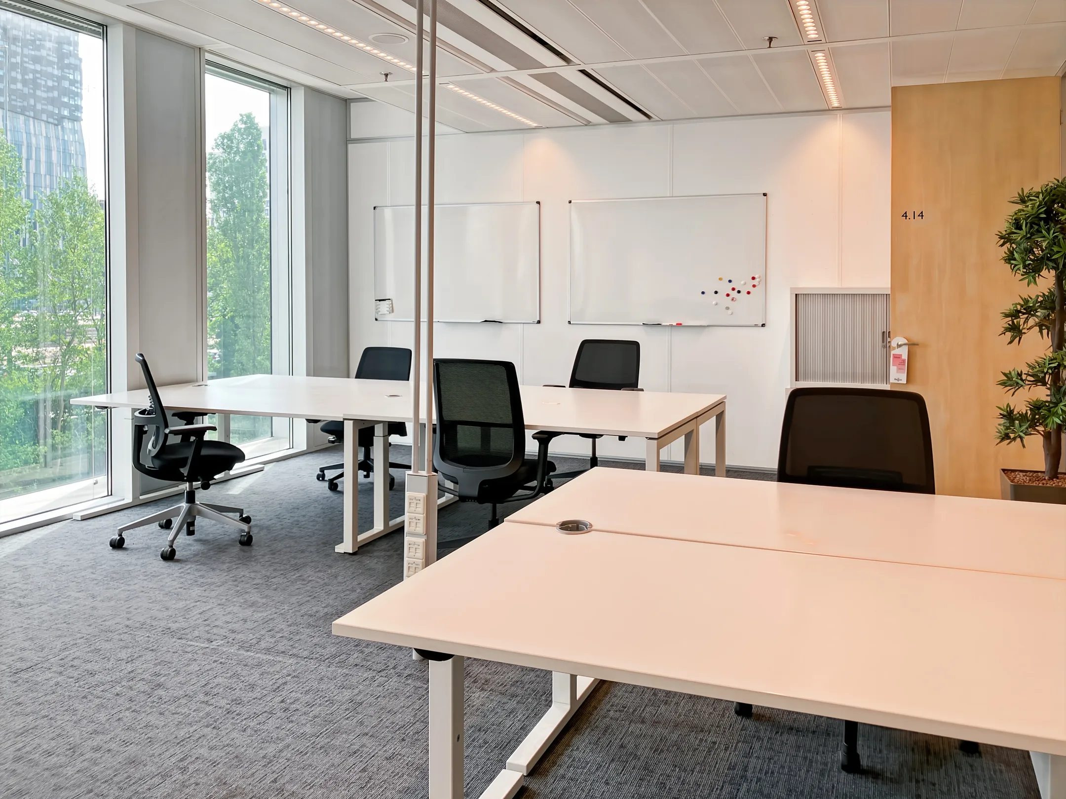 Een moderne, lichte kantoorruimte met bureaus, stoelen en grote ramen.