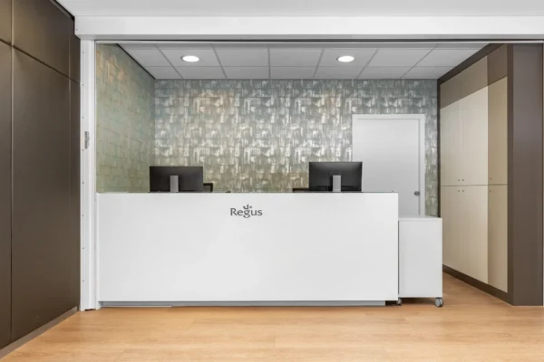 Receptiebalie van Regus met twee computermonitoren op een houten vloer.