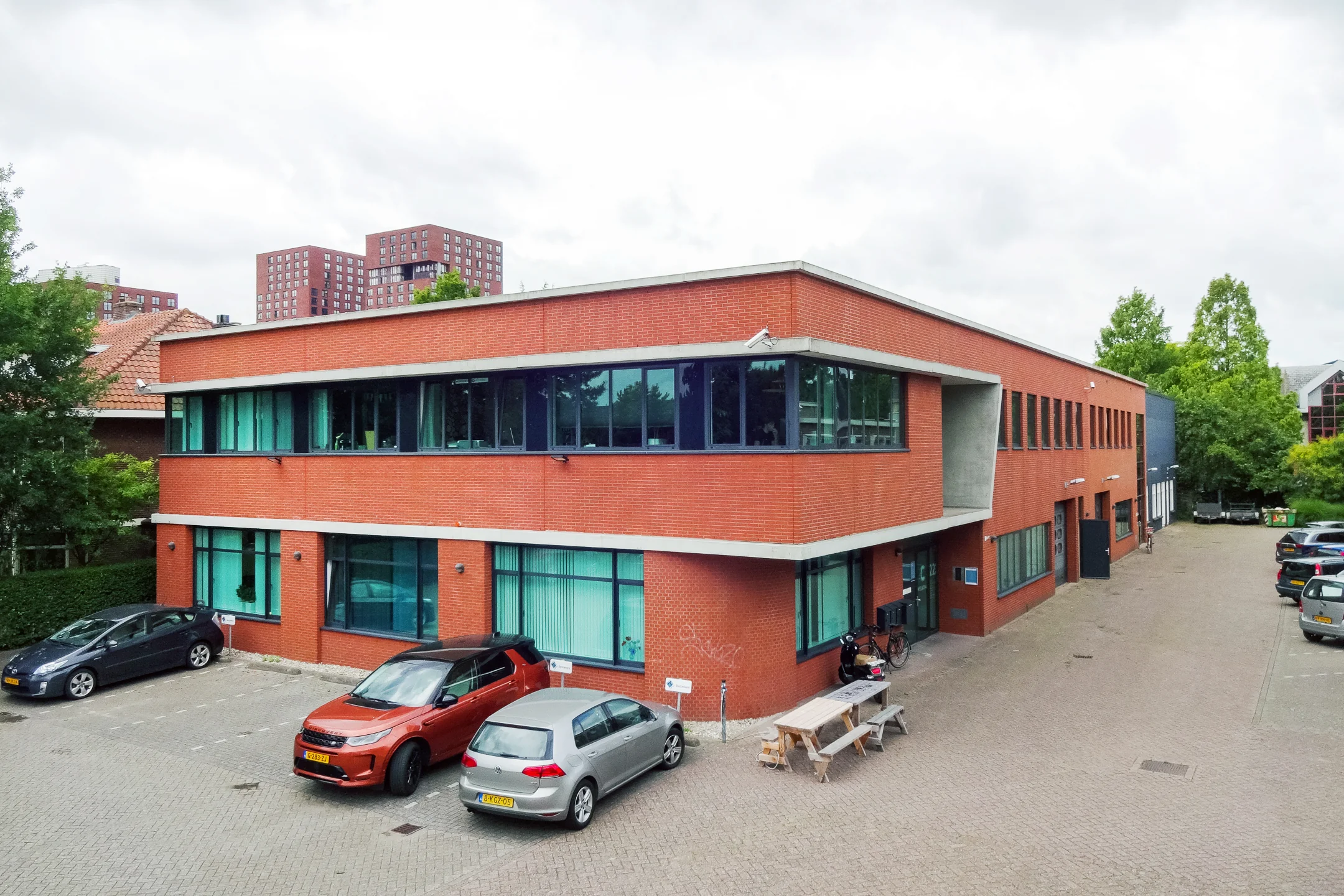 Een bakstenen kantoorgebouw met geparkeerde auto's ervoor aan de Kanaalweg.