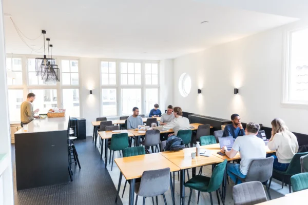 Een lichte en ruime kantoorruimte met mensen die samenwerken aan tafels.
