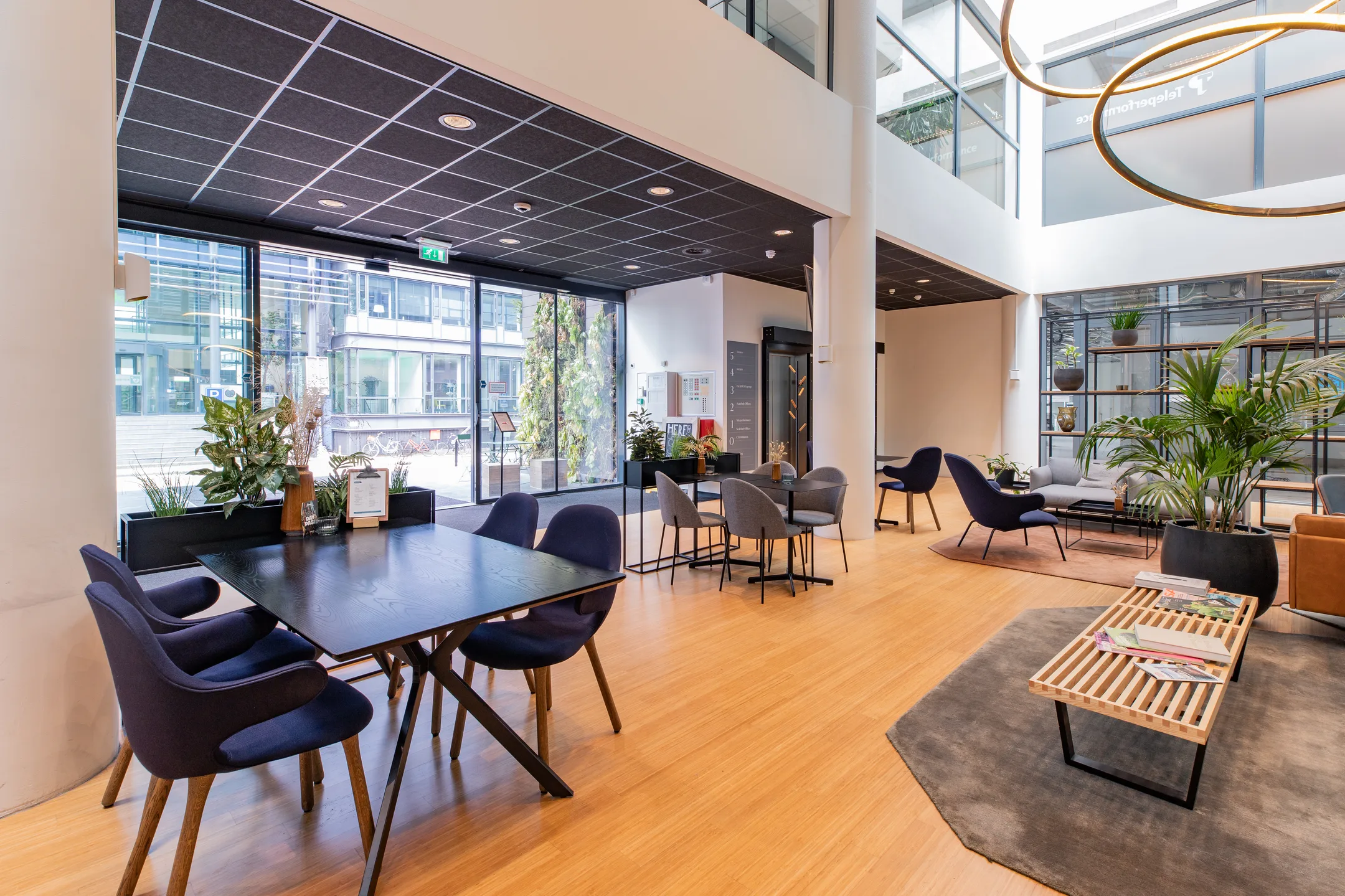 Een moderne en uitnodigende kantoorruimte met zitgedeelten en veel planten.