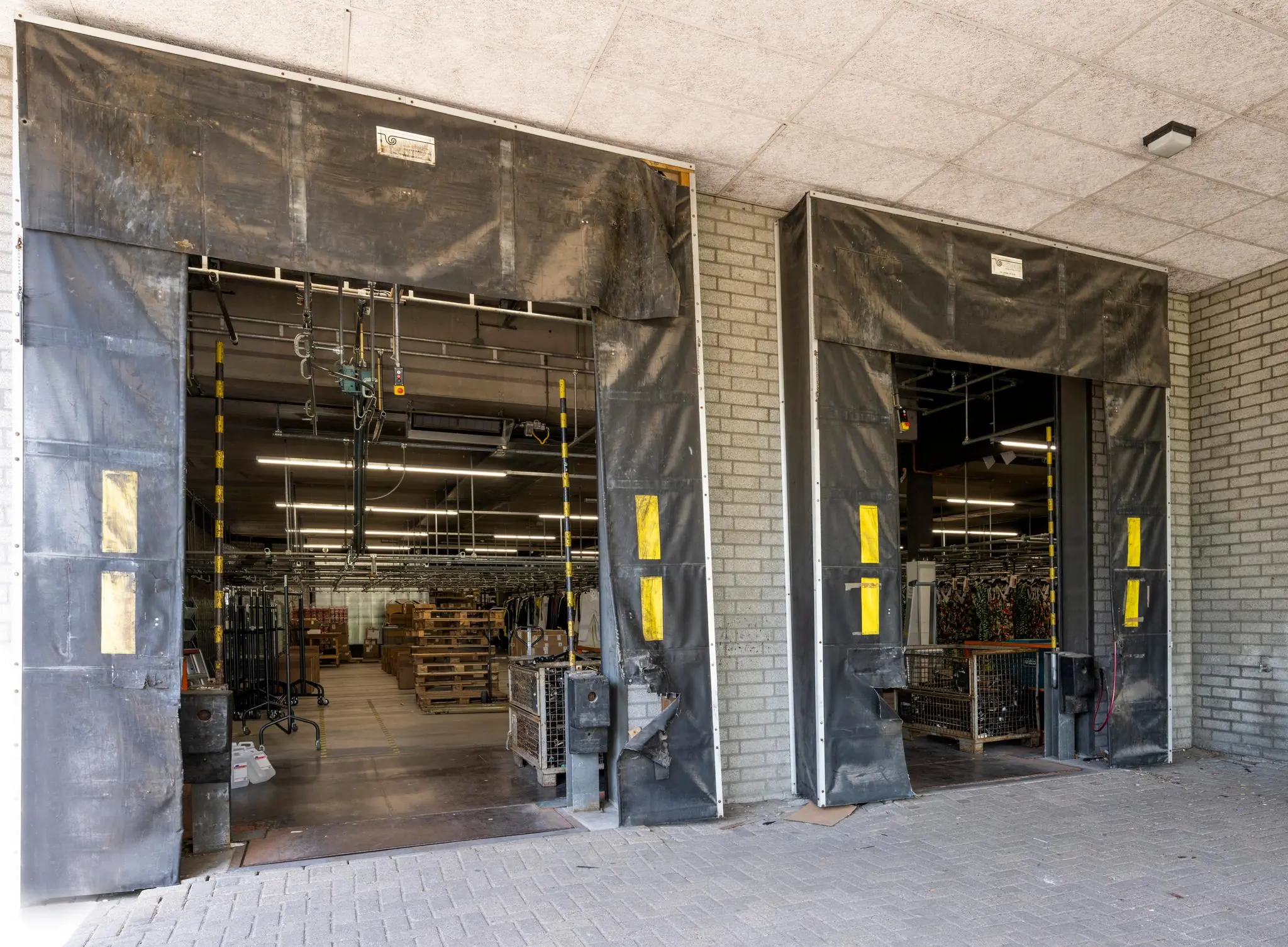 Laadperrons van magazijn Stammerhove met openstaande dockdeuren en zicht op pallets en kledingrekken binnen.