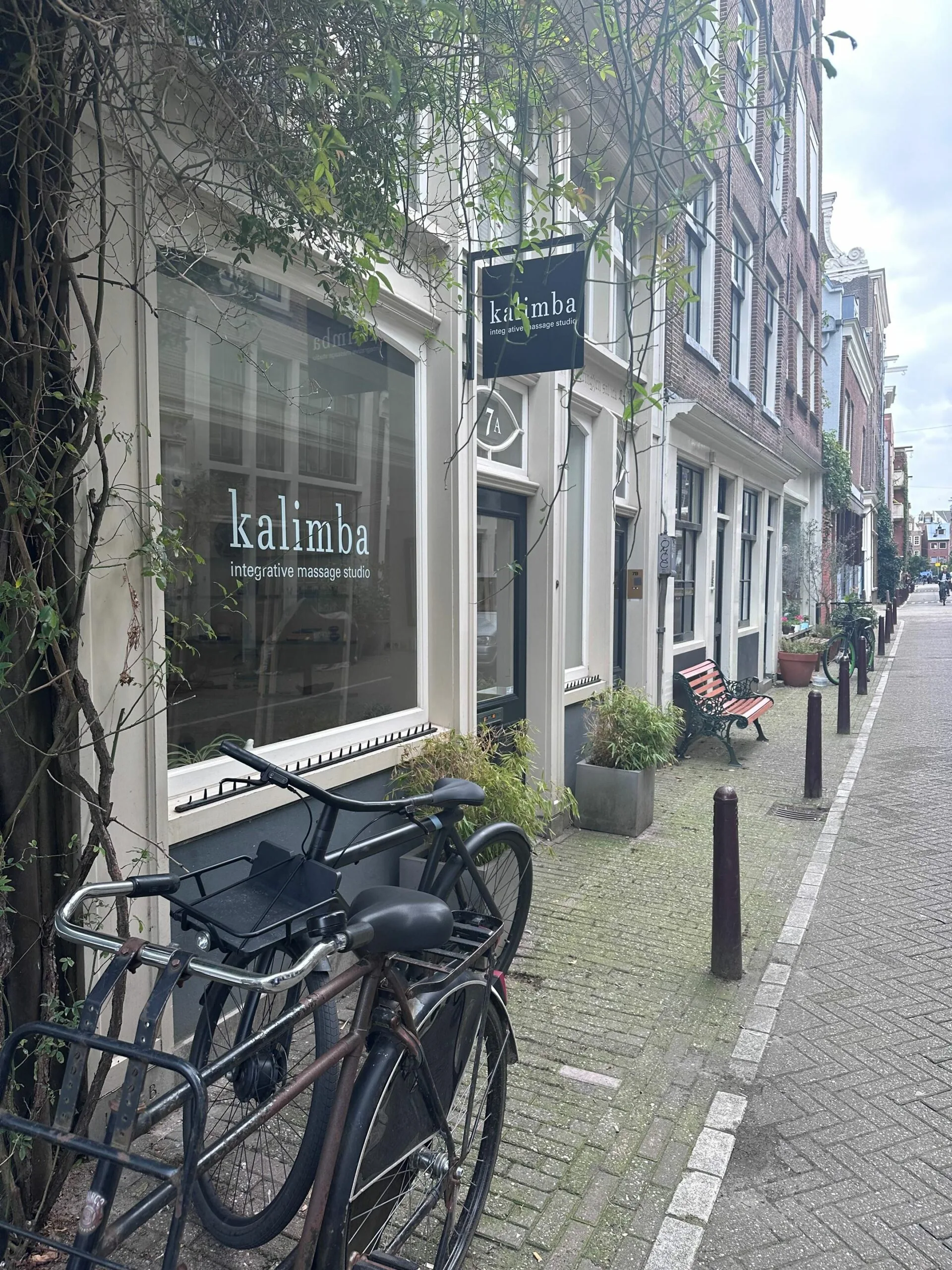 Voorgevel van Kalimba integrative massage studio in een smalle, gezellige straat met fietsen en een bankje.