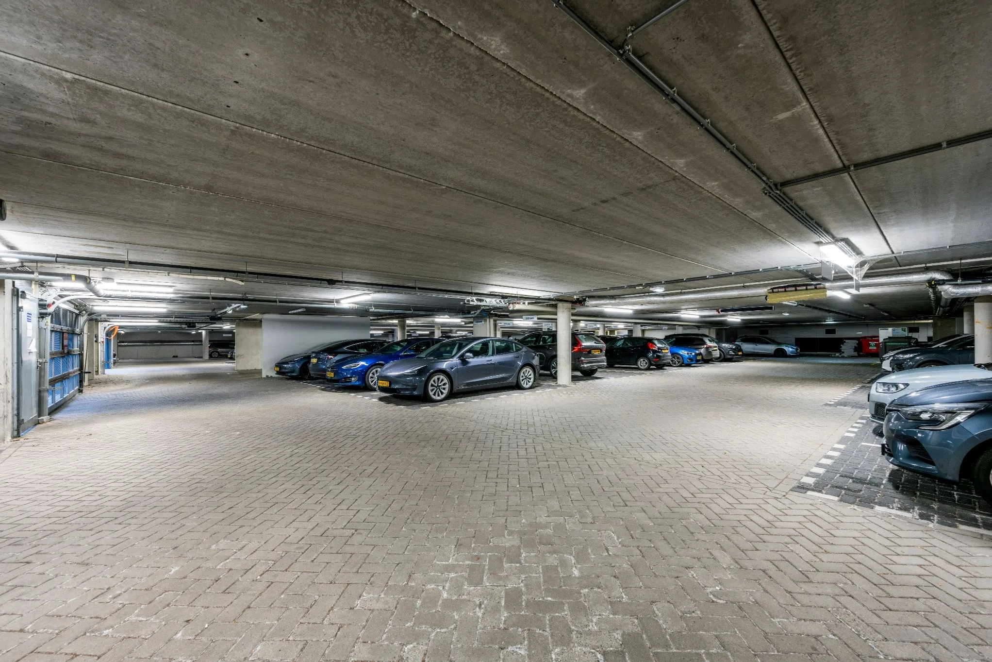Ondergrondse parkeergarage met auto's geparkeerd naast betonnen pilaren.