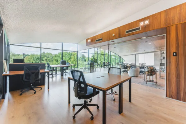 Een modern kantoor met glazen wanden, houten meubels en uitzicht op groen.