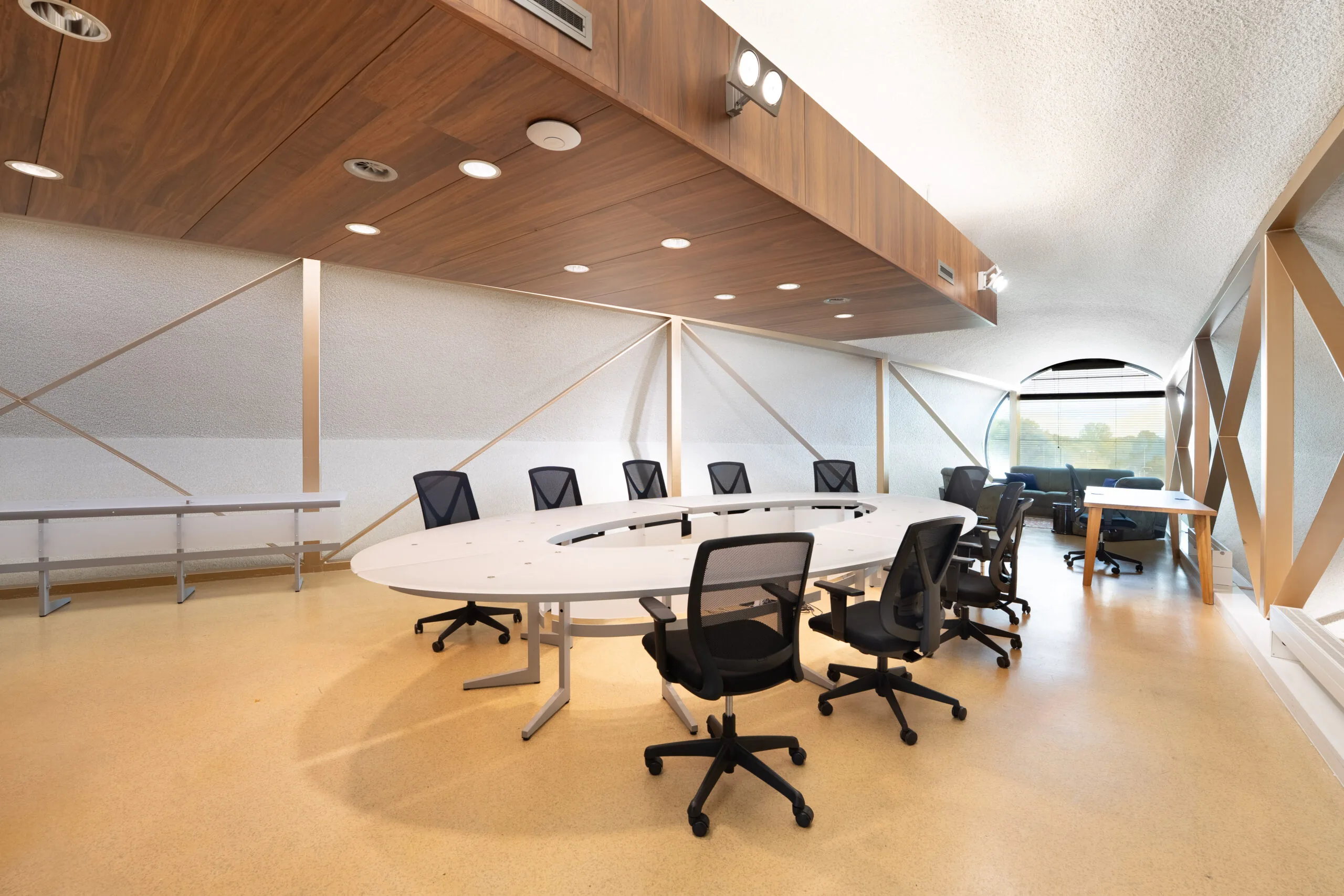 Moderne vergaderruimte met een ovale tafel en zwarte stoelen in een lichte, ruim opgezette ruimte.