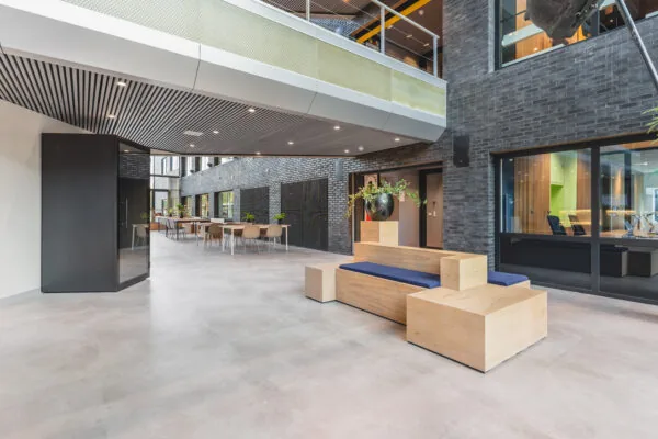 Een moderne, ruime kantoorlobby met houten meubels en grote raampartijen.
