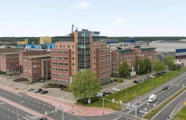 Kantoorgebouw aan de Baron van Nagellstraat 136 met meerdere verdiepingen, gelegen naast een drukke weg en omringd door industriële panden.