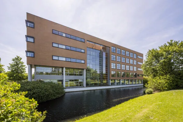 Het kantoorgebouw aan Boeingavenue 1, gelegen naast een waterpartij, met omringend groen.