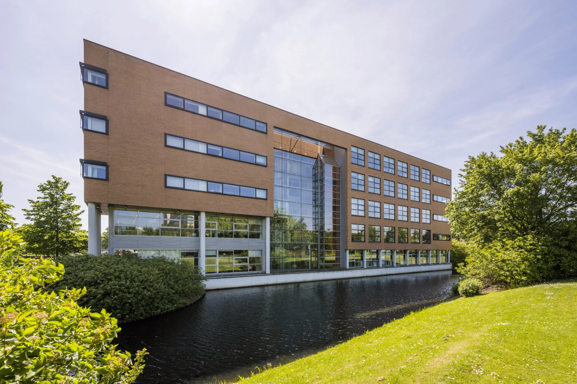 Het kantoorgebouw aan Boeingavenue 1, gelegen naast een waterpartij, met omringend groen.