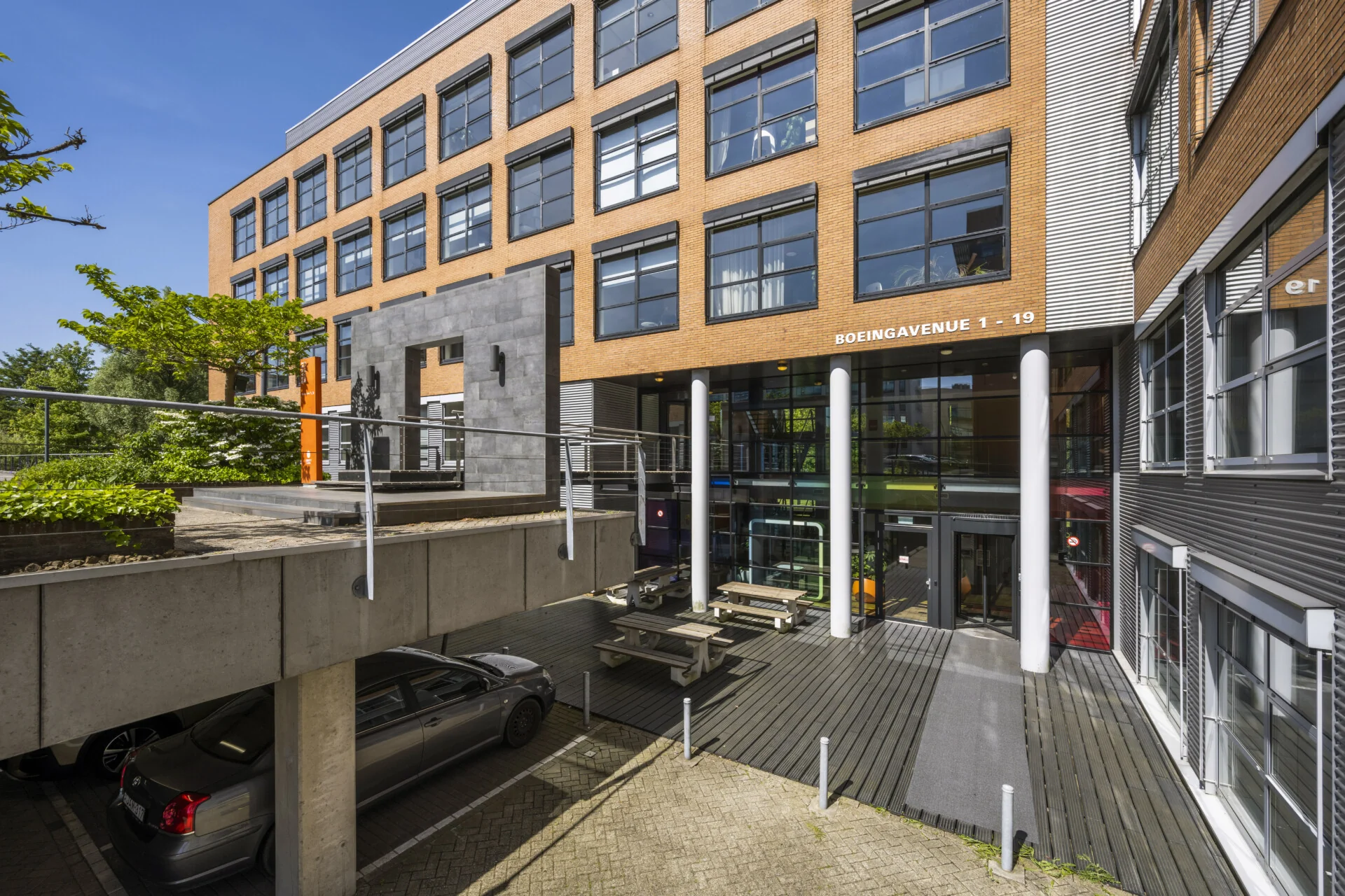 Een modern kantoorgebouw aan de Boeingavenue 1-19 met grote ramen en een parkeerplaats aan de voorkant.