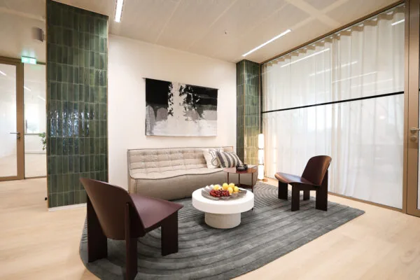 Moderne wachtruimte in Co-Office Valley Amsterdam met een bank, twee stoelen, een ronde salontafel en gedempte verlichting.