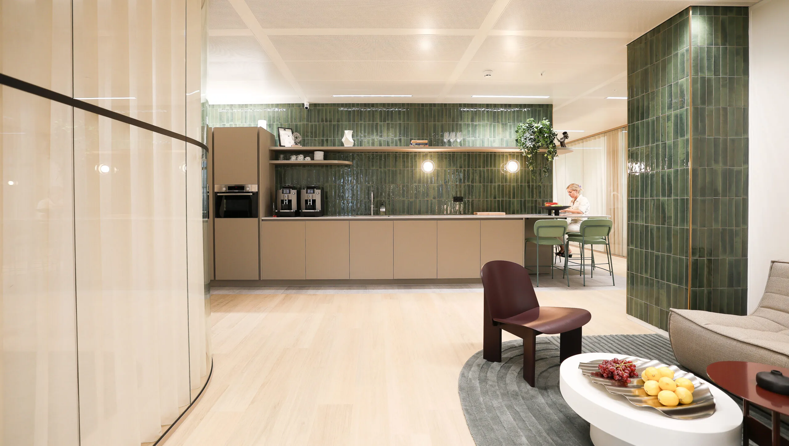 Moderne kantoorkeuken in Co-Office Valley Amsterdam met groene wandtegels, ingebouwde koffiemachines en een zithoek op de voorgrond.