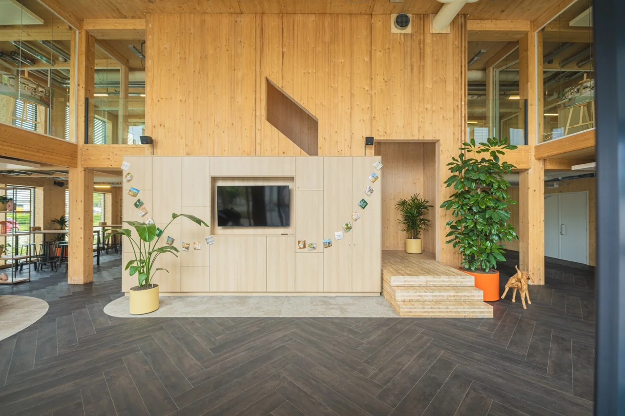 Modern houten kantoorinterieur met planten, een televisiewand en decoratieve kaartenlijn.