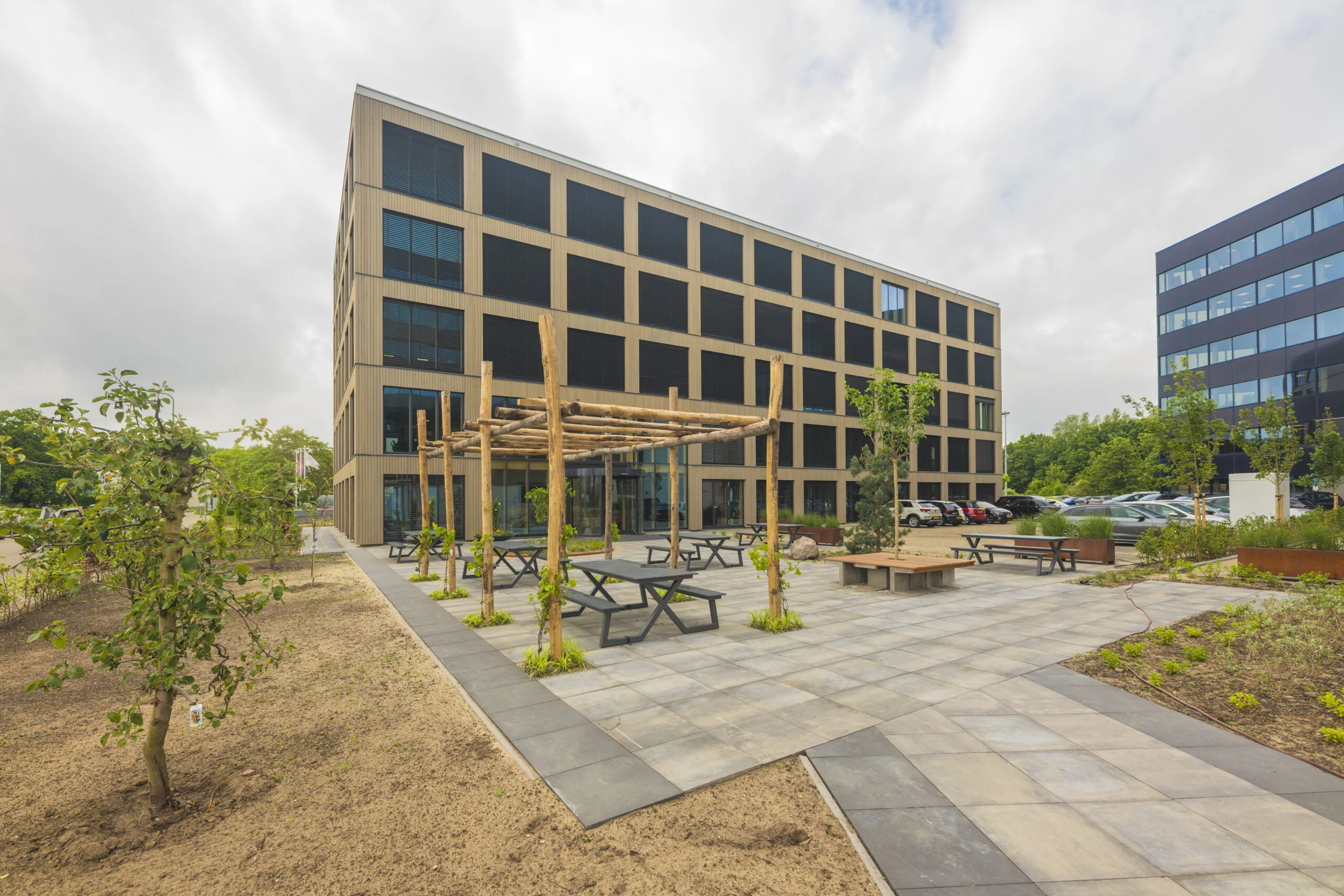 Moderne kantoorgebouw _DSC3189-Verbeterd-NR met een groen ingericht buitenterrein met zitplaatsen en pergola.