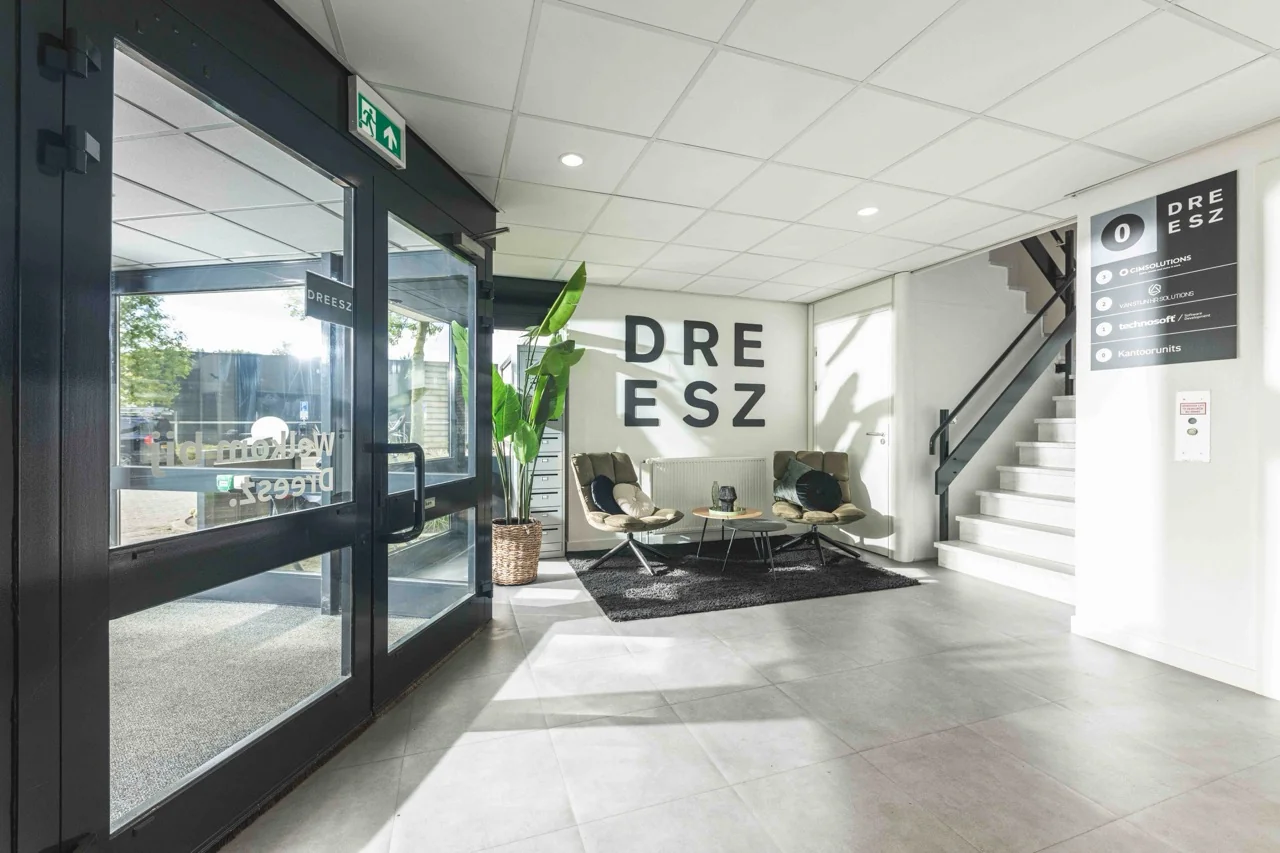 Moderne en lichte entreehal van het kantoorpand Dreesz met zitgelegenheid en bedrijfsnaam op de muur.