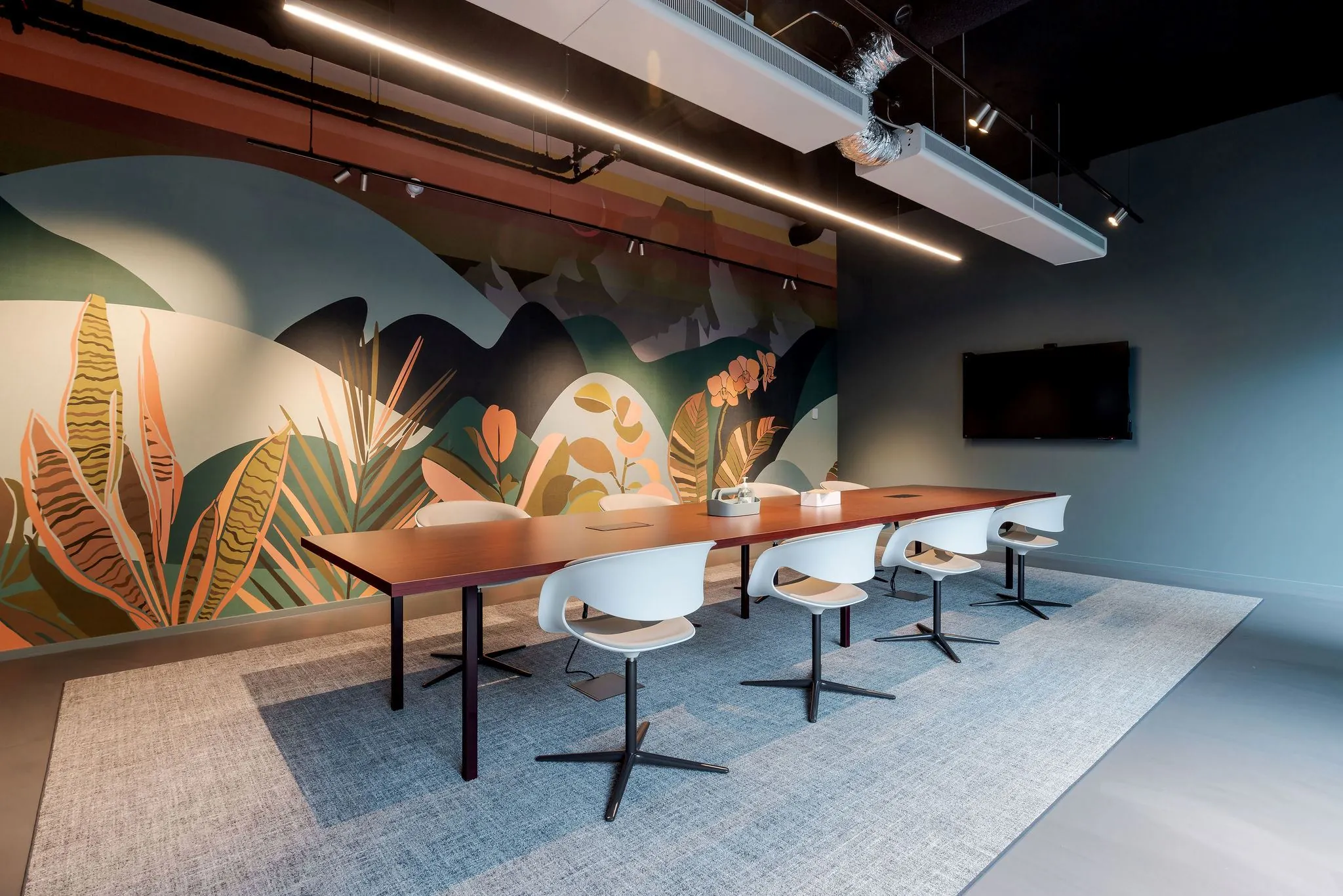 Vergaderruimte aan de Daalsesingel 51 met lange tafel, moderne stoelen en kleurrijk plantenmotief op de muur.