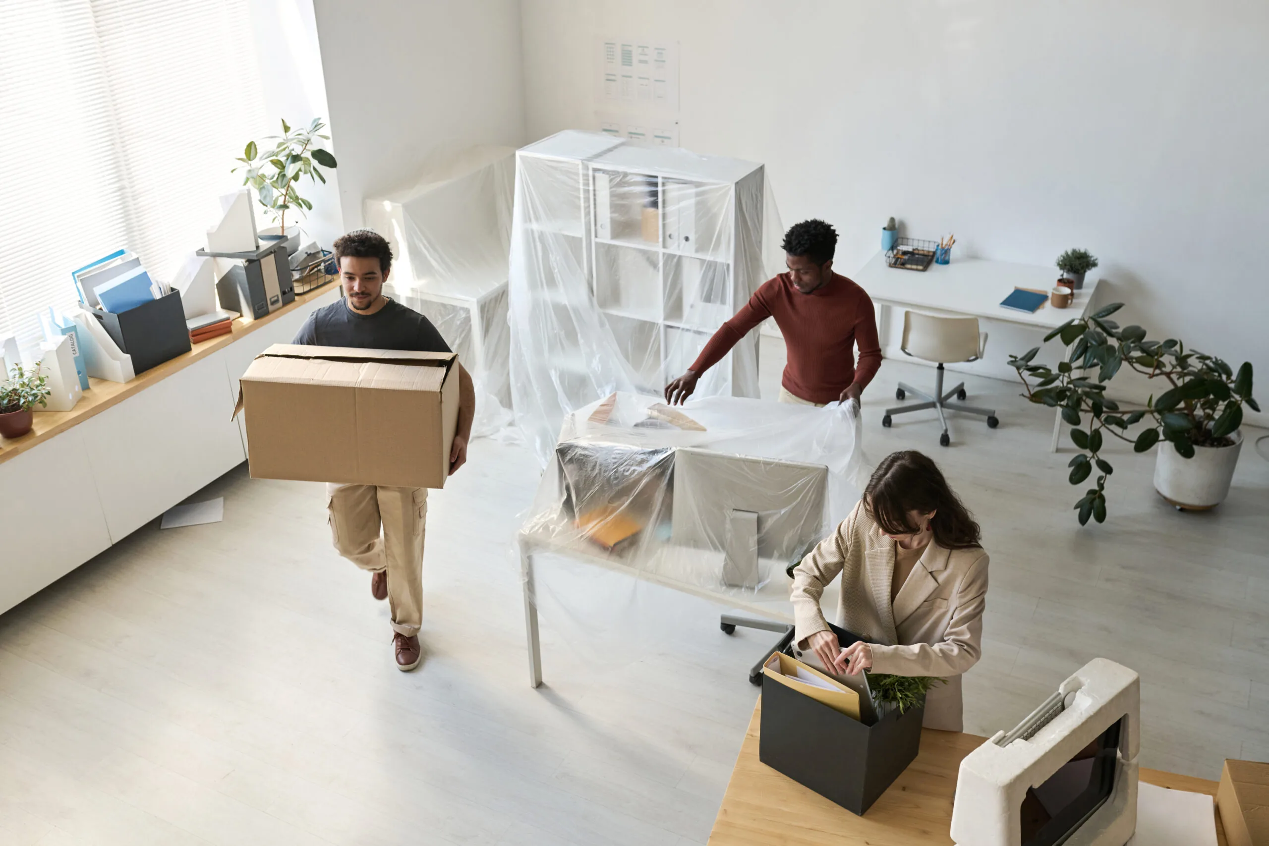 Business people unpacking boxes and setting up furniture in a new office space.