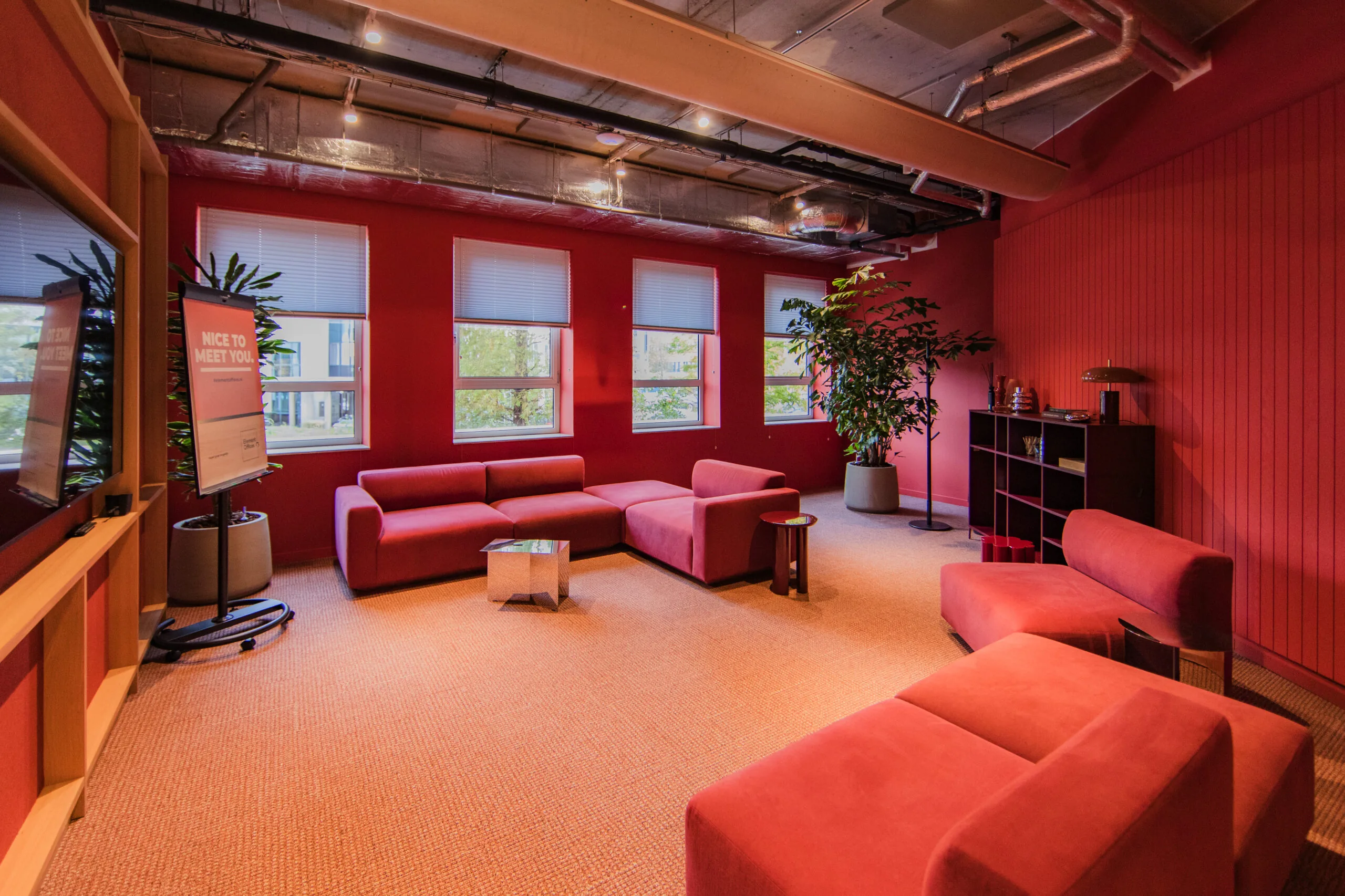 Modern lounge area at Hullenberg with red walls, matching red seating, and large windows letting in natural light.