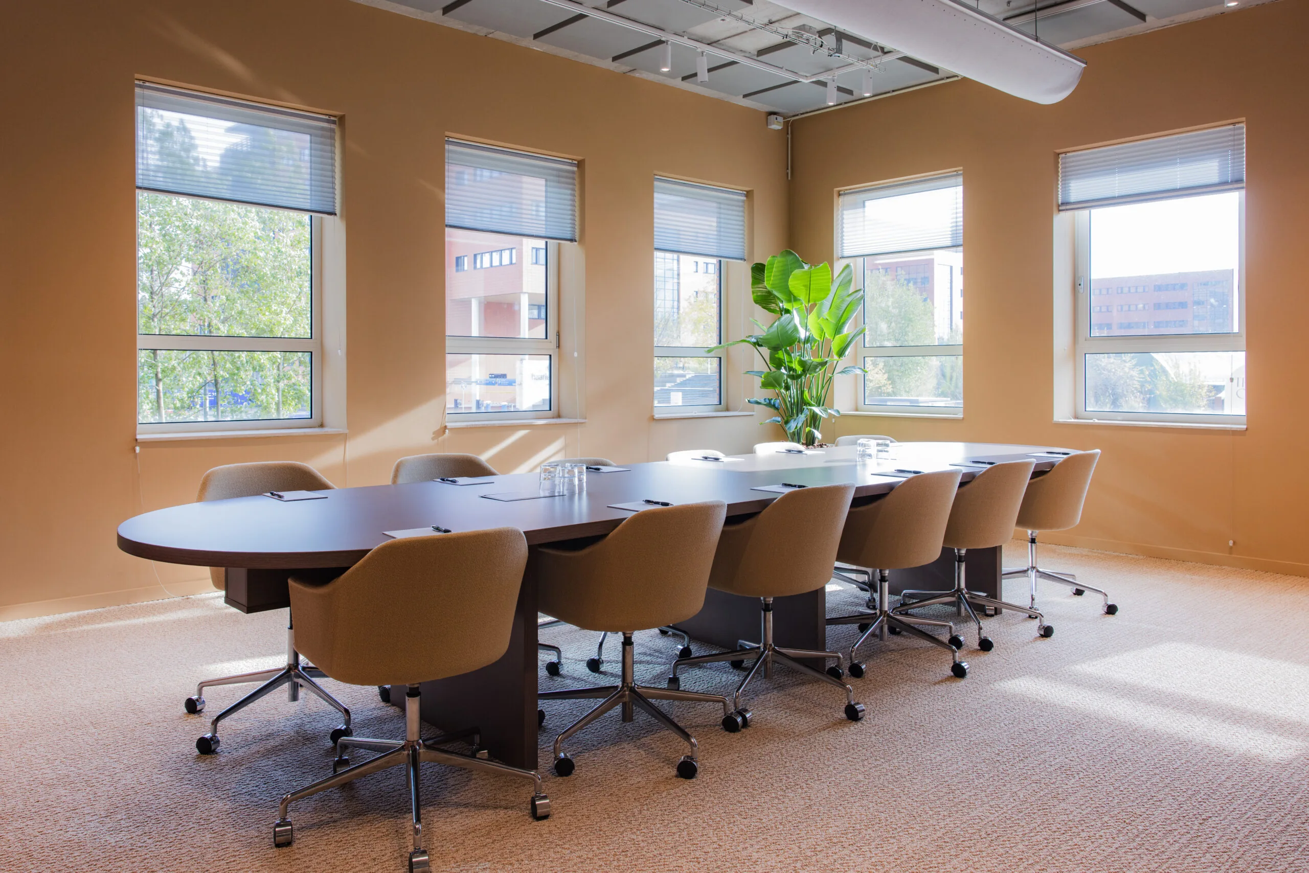 Modern conference room at Hullenberg with large windows, a long meeting table, and beige swivel chairs.