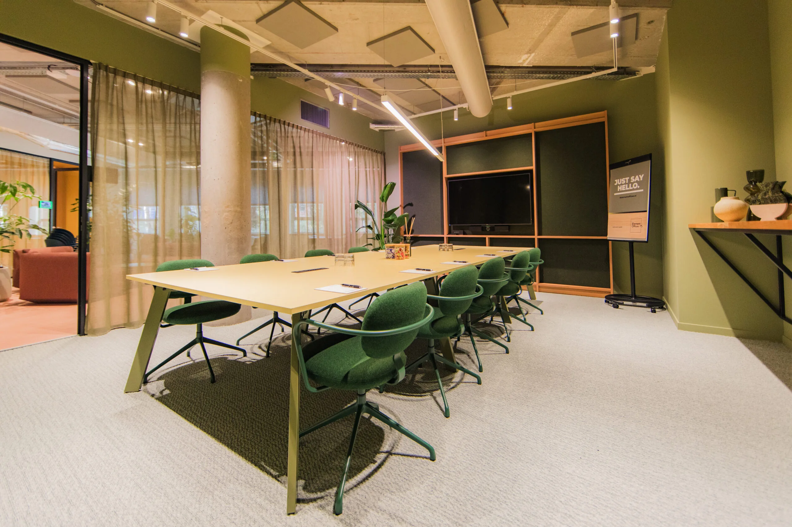 Modern conference room at Hullenberg ELE2510 with green chairs, a large meeting table, and a presentation screen.