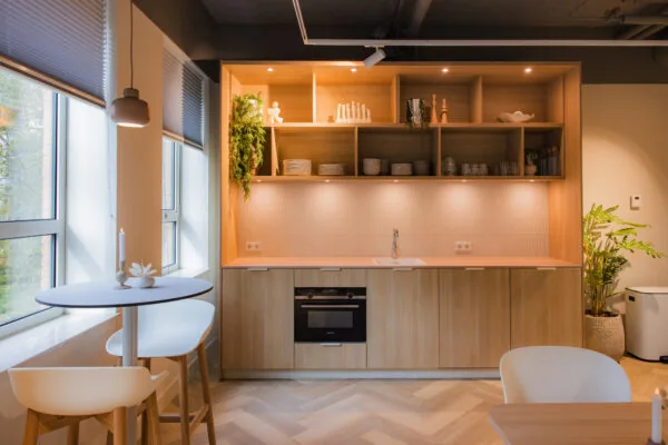 Modern kitchenette in Hullenberg 107 with light wood cabinets, open shelving, and minimalistic decor.