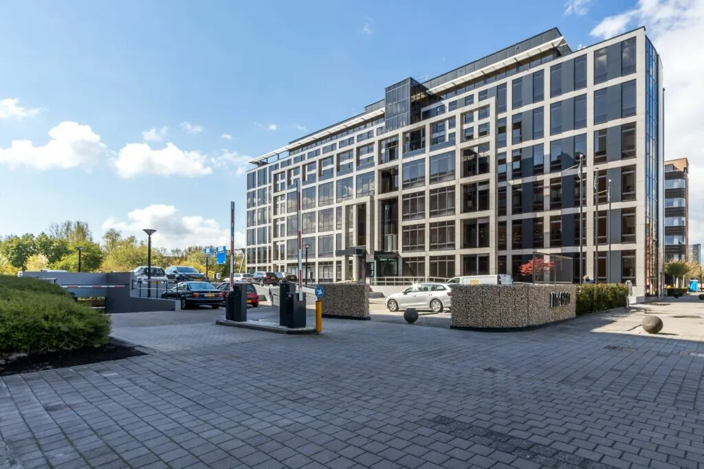 Modern kantoorgebouw aan de Euclideslaan 265 met parkeergarage en auto’s op de voorgrond.