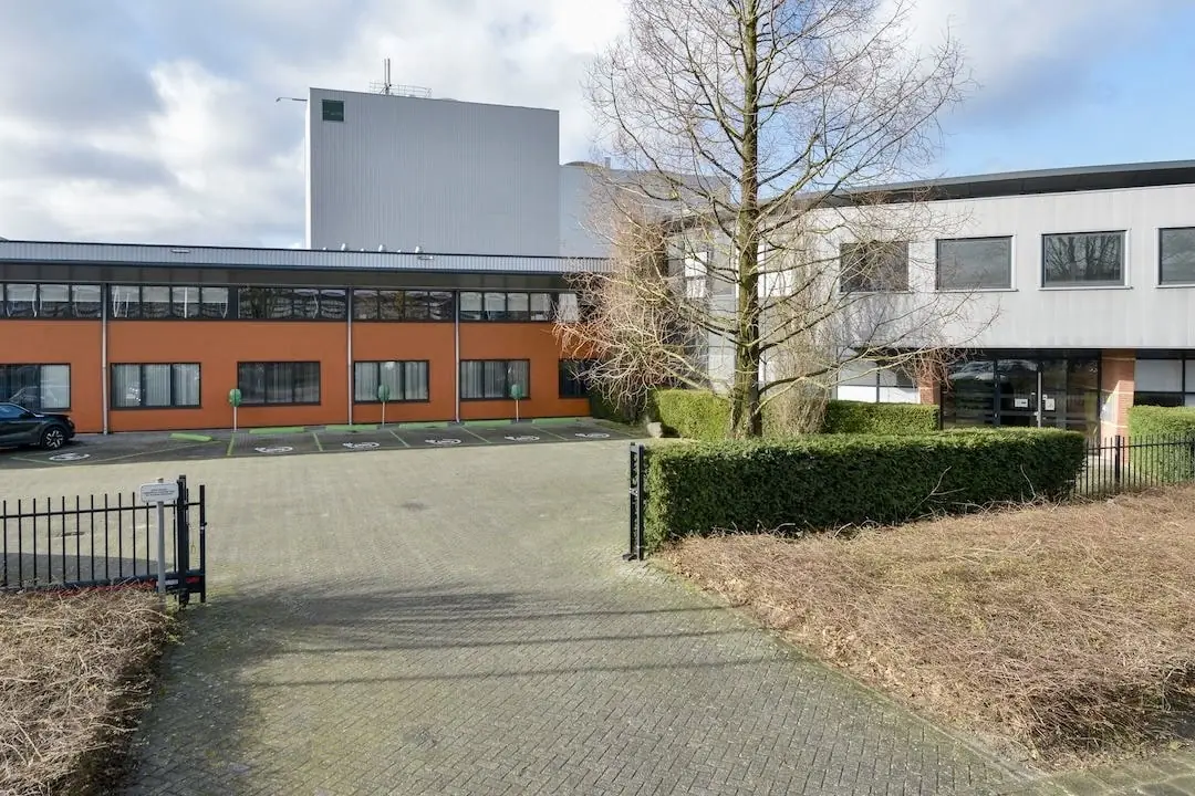 Vooraanzicht van het kantoorpand FlexOffiZ aan de Heliumweg 18 in Amersfoort met parkeerplaatsen en omheining.
