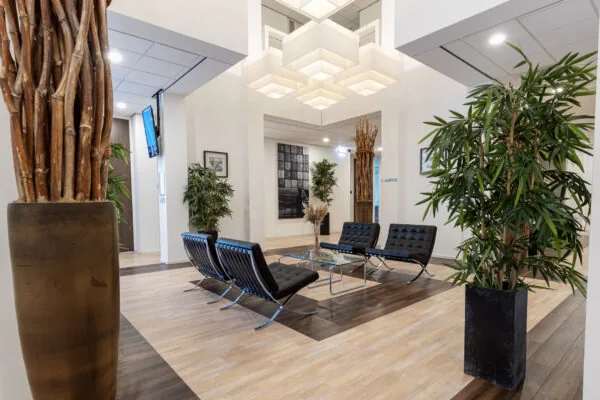 Moderne wachtruimte aan de Fonteinlaan 5 in Haarlem met designstoelen, glazen salontafel, grote planten en opvallende plafondlampen.