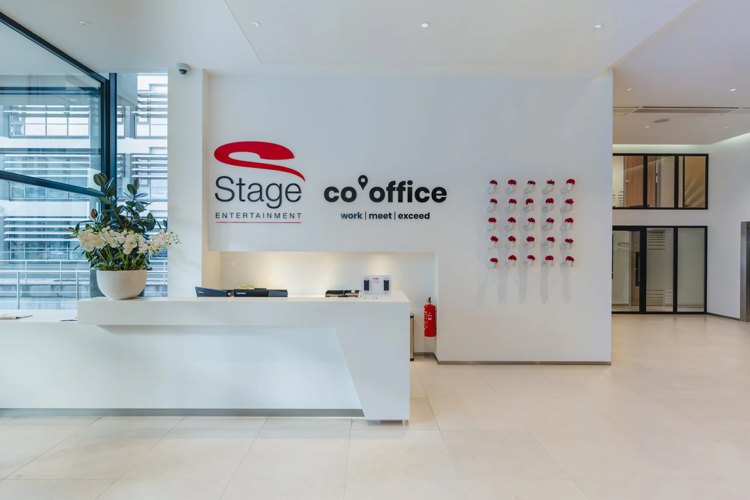 Moderne receptiebalie van Stage Entertainment en co. office met strakke witte inrichting en een bloemenwand.