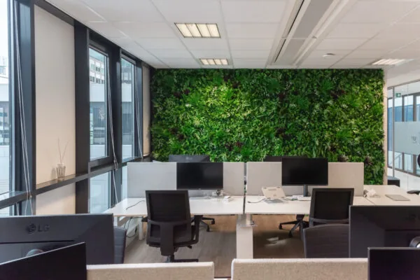 Moderne kantoorruimte met werkplekken en een groene plantenwand als eyecatcher.