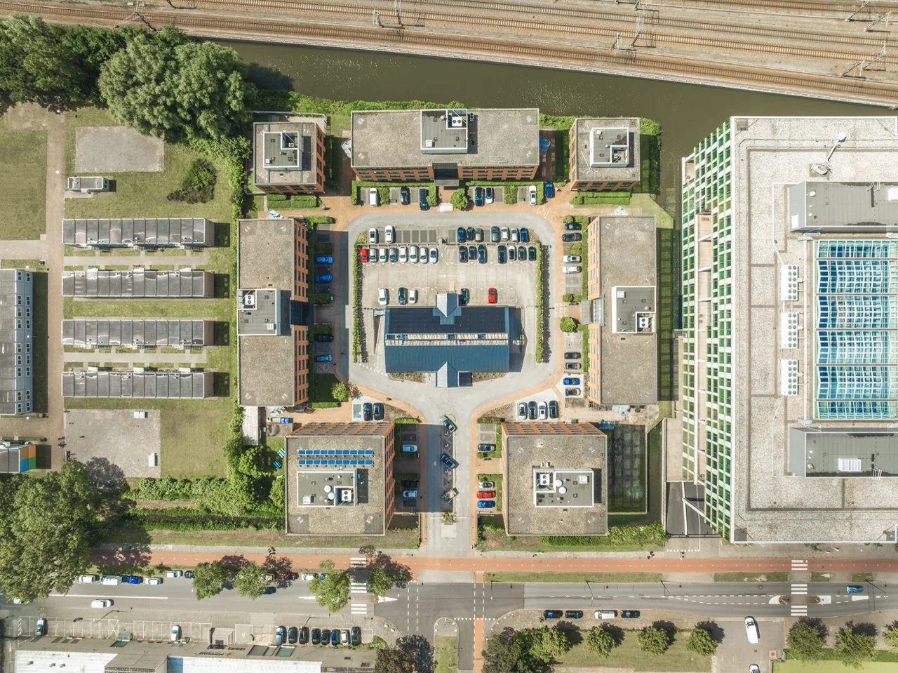 Luchtfoto van een complex met meerdere kantoorgebouwen rondom een centraal parkeerterrein, getiteld Gebouwen 11 groot.