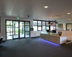 Moderne receptieruimte met een balie, computers en sfeerverlichting, gelegen bij een glazen entree.