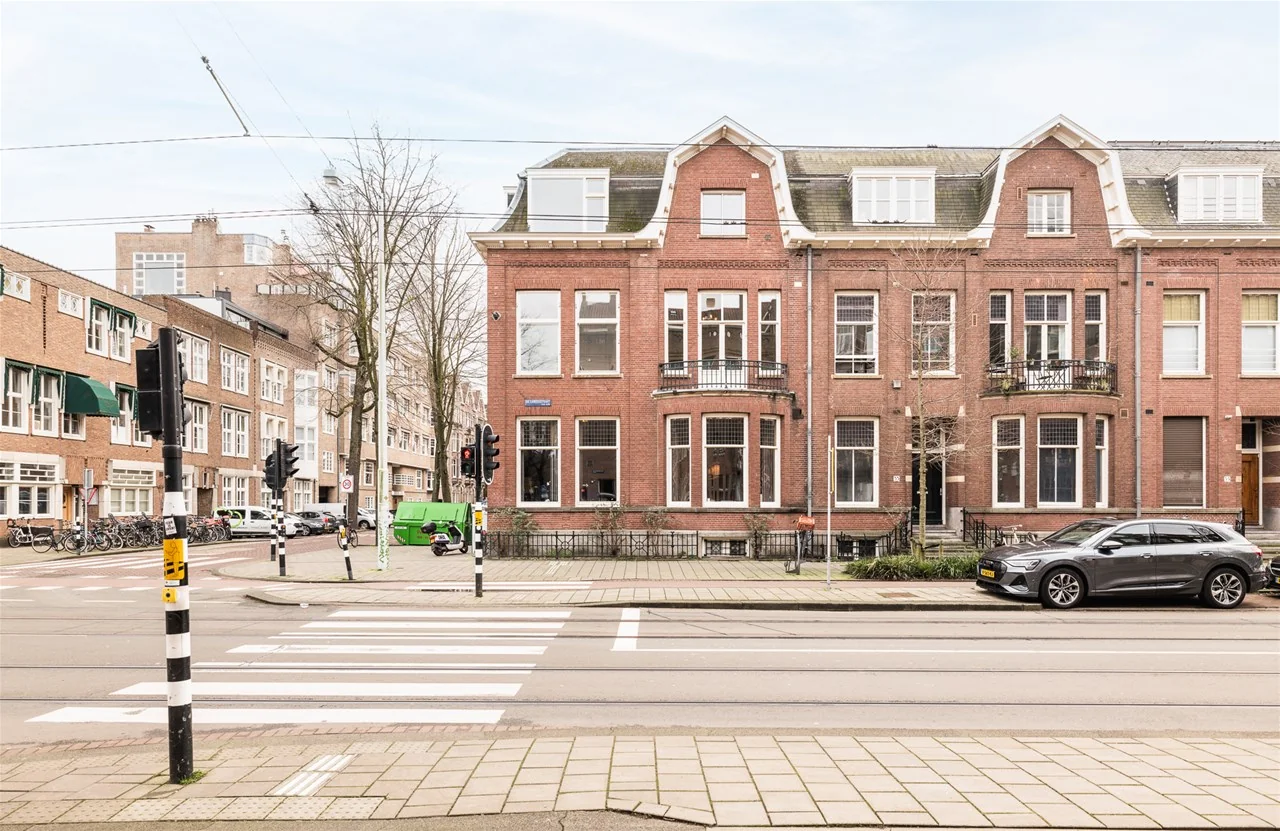 Straatbeeld met een karakteristiek rood bakstenen herenhuis op Jacob Obrechtstraat 10 in Amsterdam.
