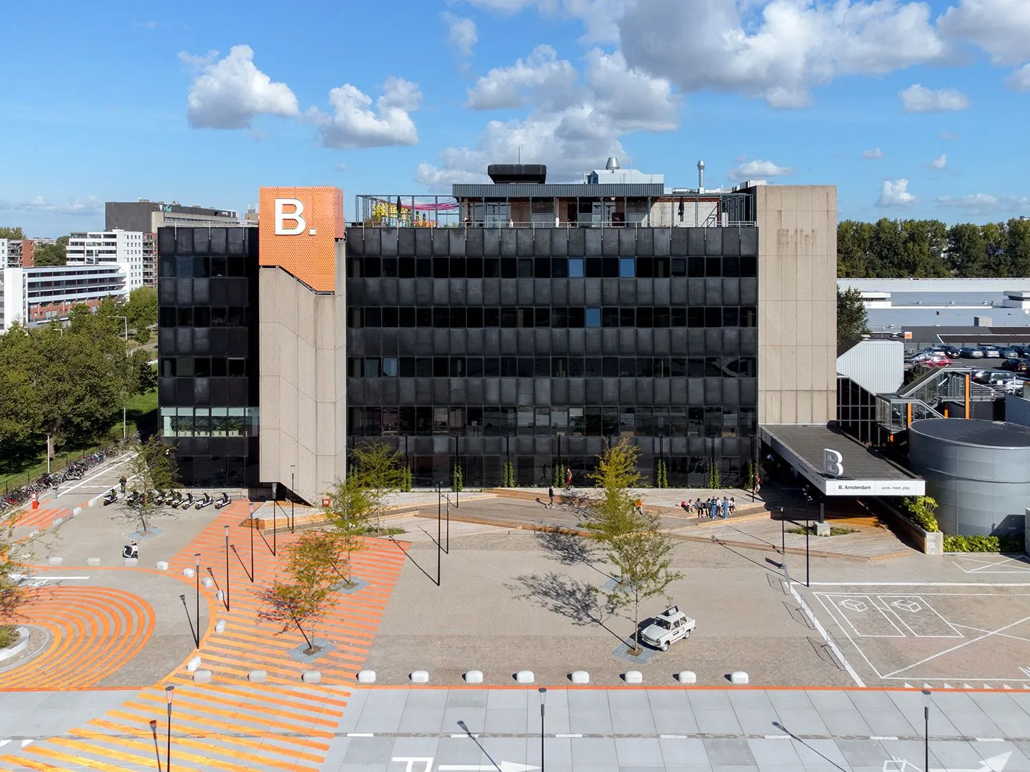 Kantoorgebouw B. Amsterdam aan de Johan Huizingalaan 763a, gezien vanaf de voorzijde met plein en opvallende oranje lijnen.