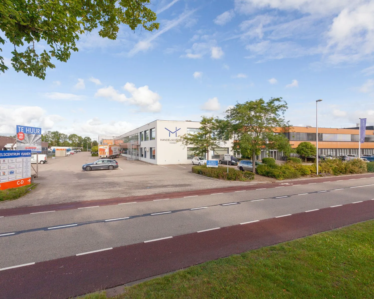 Bedrijfsverzamelgebouw Handelscentrum Vianen aan De Limiet 15 met parkeerplaatsen en een groot "Te Huur"-bord zichtbaar vanaf de straat.