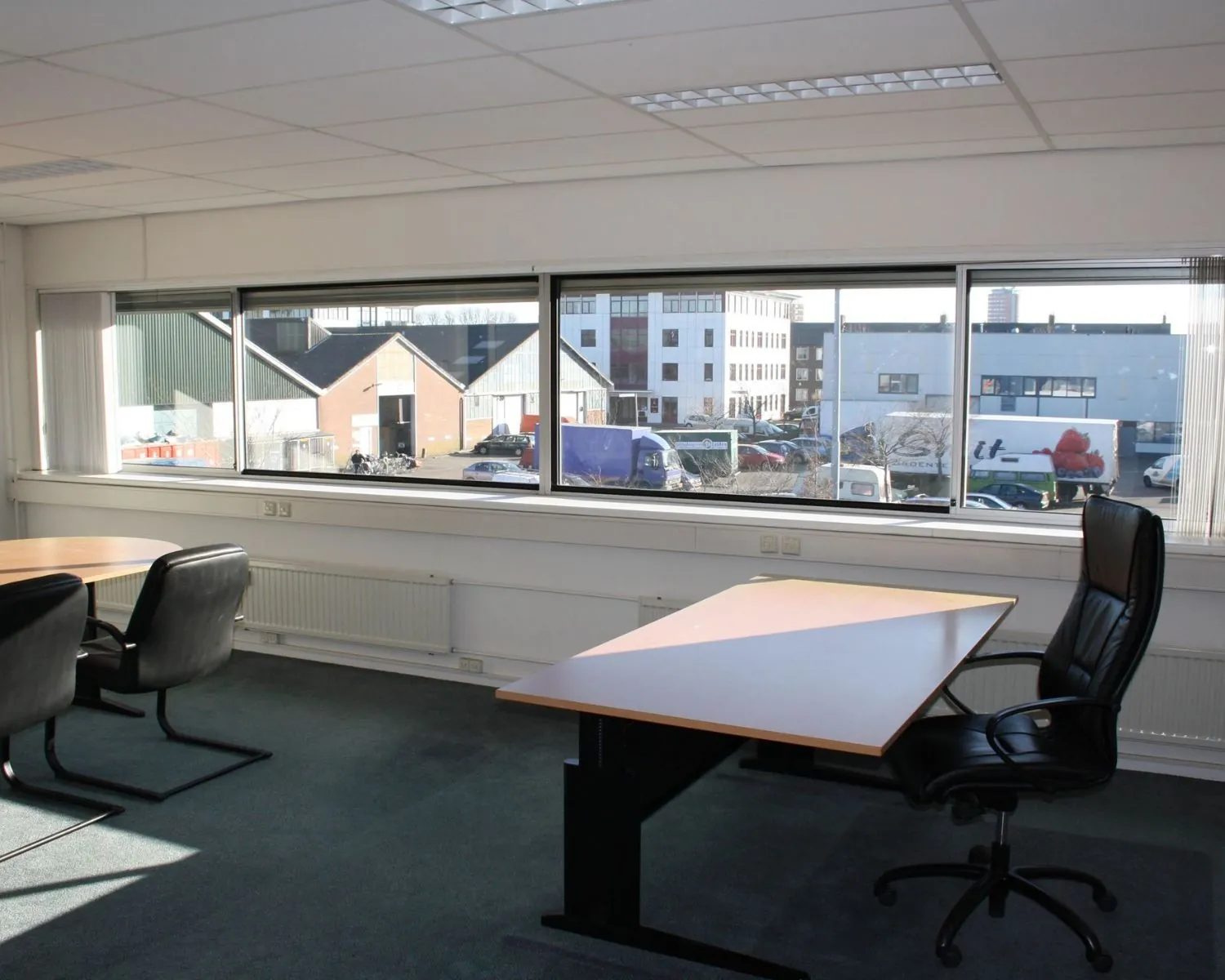 Lichte kantoorruimte met bureaus en stoelen aan de Fruitweg 16-30, met uitzicht op een bedrijventerrein.