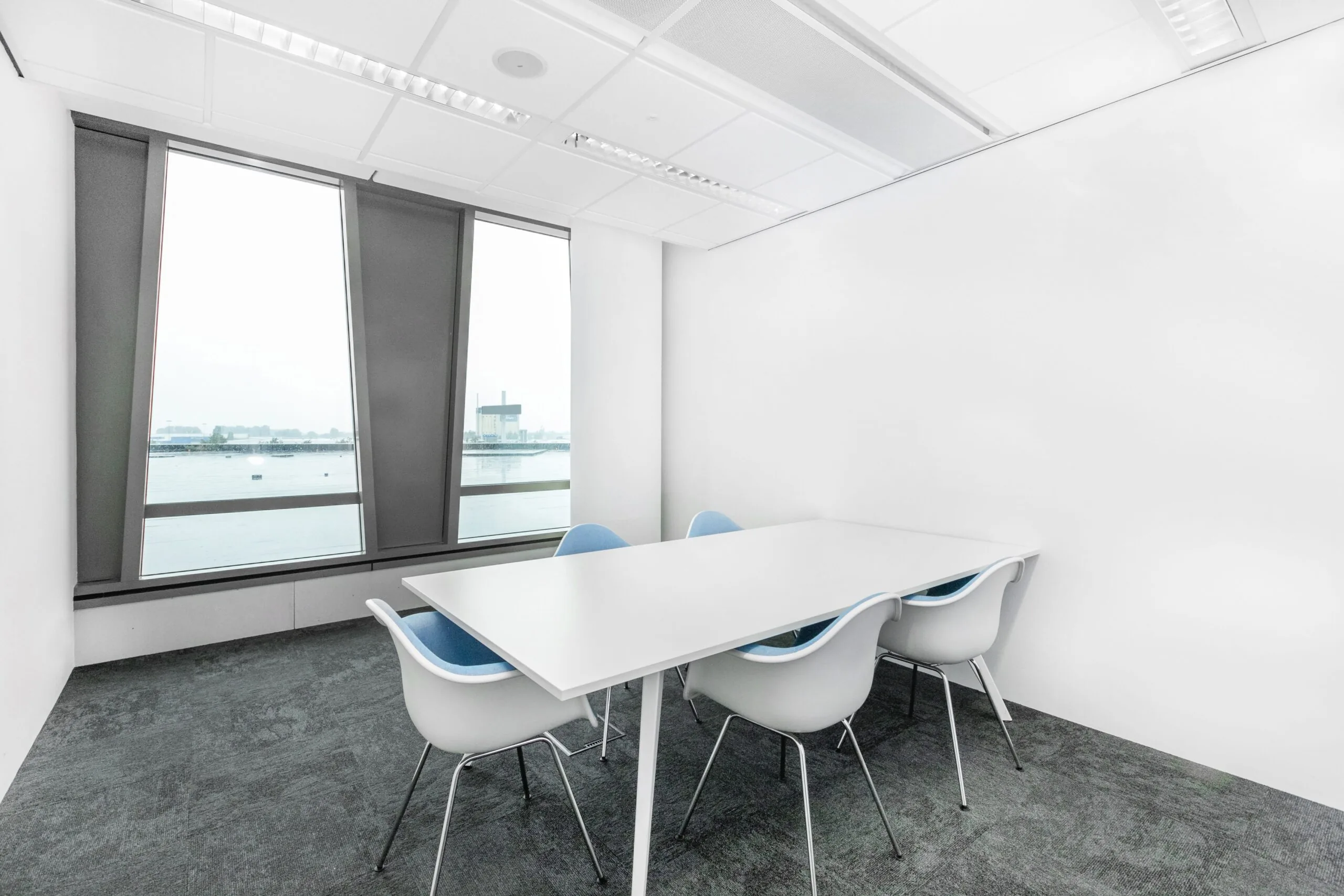 Lichte kantoorruimte in Zwolle met witte tafel, zes stoelen en uitzicht op het water.