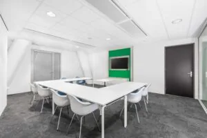 Moderne vergaderruimte met witte tafels, designstoelen en een flatscreen aan de muur in een kantoor aan de Grote Voort 293a in Zwolle.