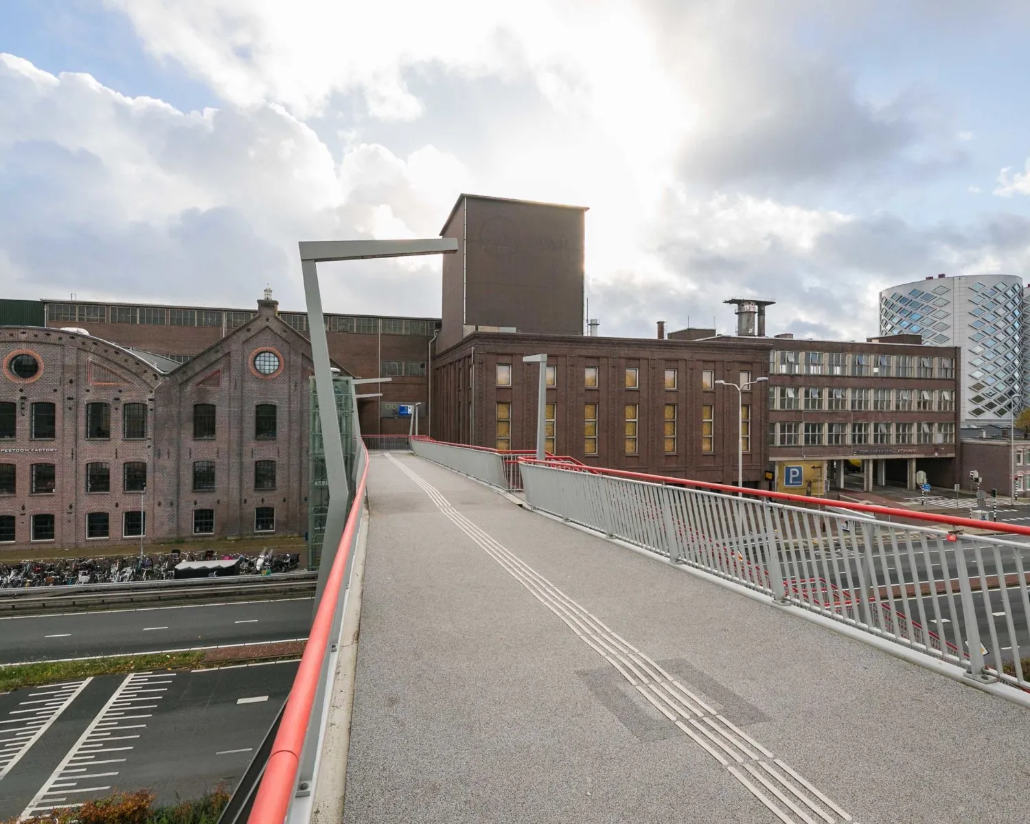 Voetgangsbrug richting kantoorpand aan de Haarlemmerstraatweg 11 in Halfweg met omliggende industriële en moderne gebouwen.