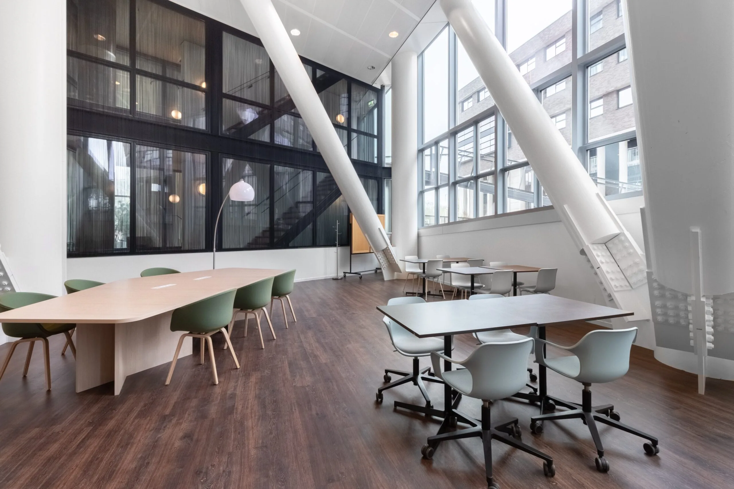 Moderne kantoorruimte in Kennedy Tower Eindhoven met grote ramen, houten vloer en diverse werkplekken.
