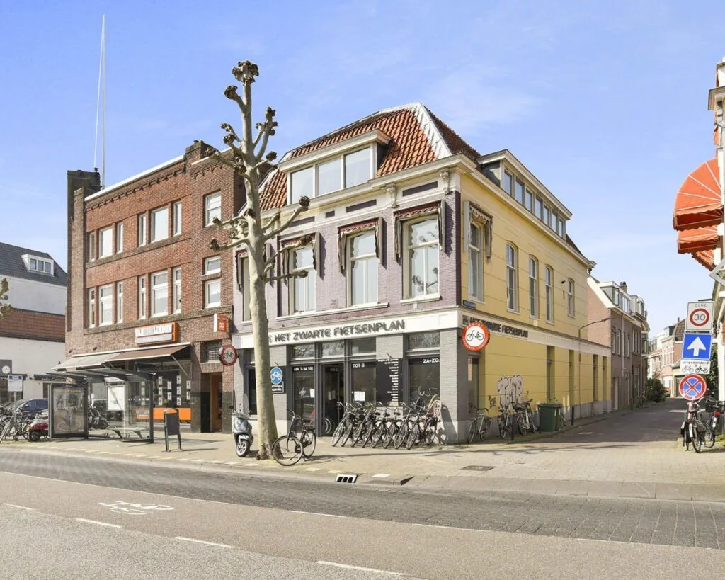 Straatgezicht met een hoekpand aan Houtplein 22 in Haarlem met fietsen voor de deur en een bushalte links.