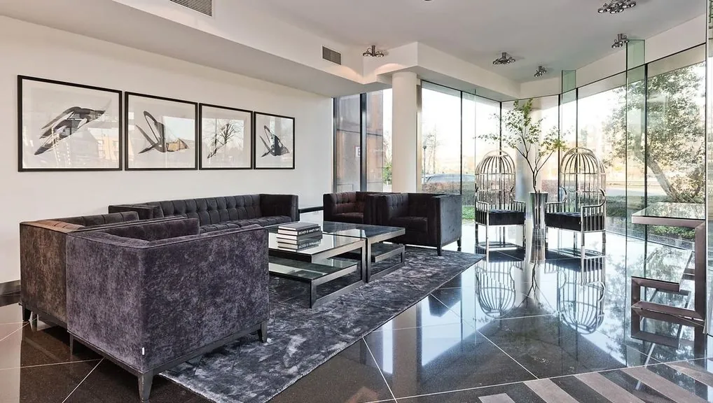 Moderne en stijlvolle wachtruimte in kantoorgebouw Kennemerhaghe met glazen wanden, luxe meubels en kunst aan de muur.