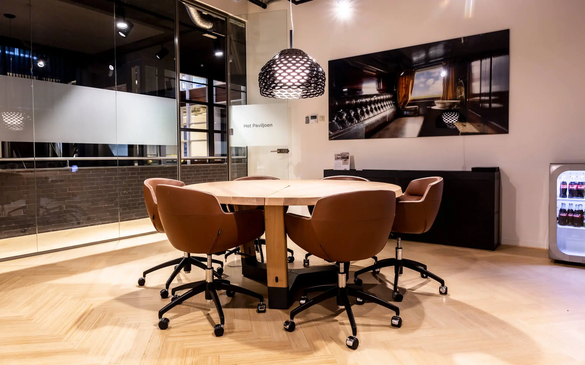 Moderne vergaderruimte met ronde houten tafel, leren stoelen en glazen wanden in kantoor aan het Kennemerplein 6-14 in Haarlem.
