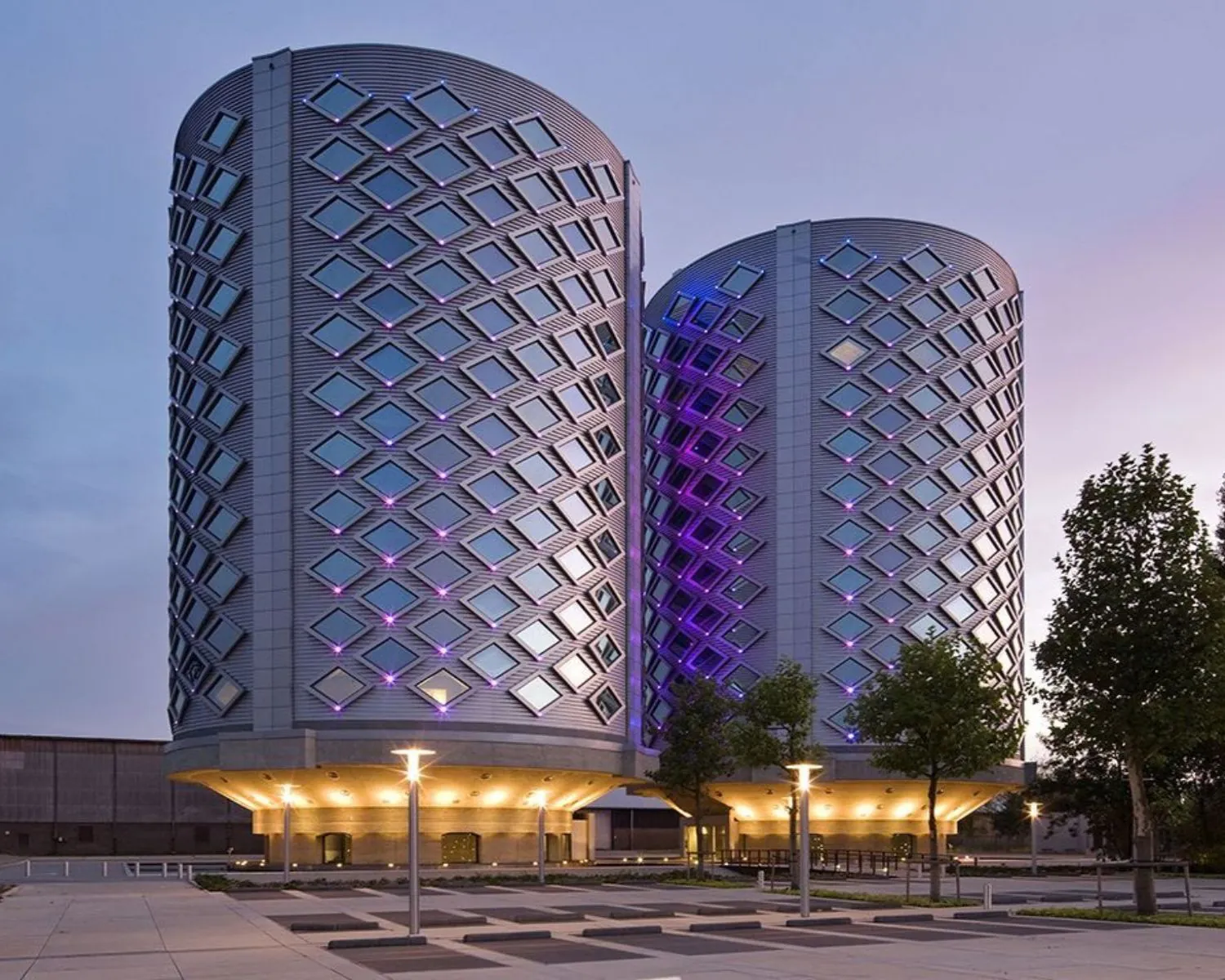 Twee moderne kantoorgebouwen van SugarCity in Halfweg met opvallende gevelverlichting in het schemerlicht.
