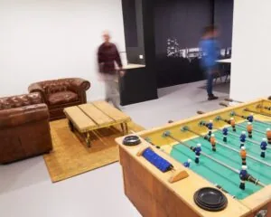 Gemeubileerde kantoorruimte aan de Ukkelstraat 2 in Eindhoven met leren zithoek, tafelvoetbaltafel en werkruimte op de achtergrond.