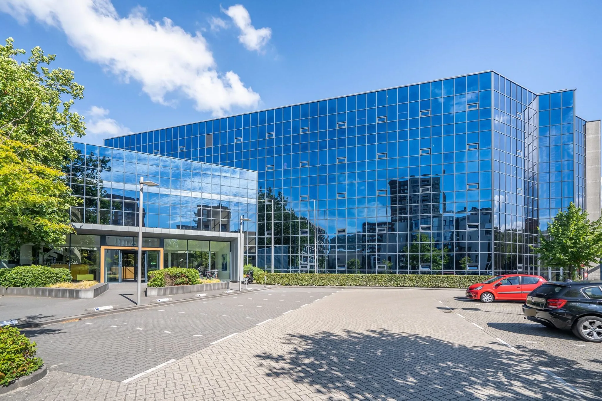 Modern kantoorgebouw Kanaalpark 140 met een gevel van spiegelend glas en een parkeerplaats op de voorgrond.