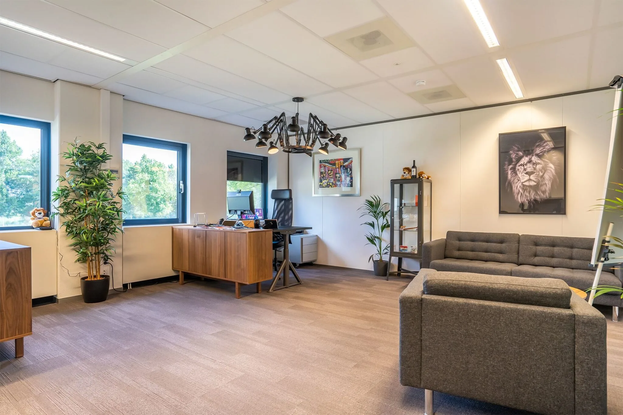 Modern ingericht kantoor met een bureau, zithoek, kunst aan de muur en grote ramen in Kanaalpark 140.